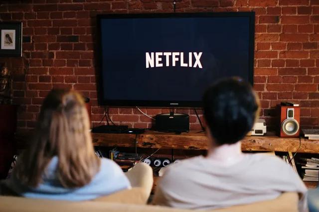 A couple relaxing and watching Netflix in a cozy living room setting. Telewizja i CTV w planowaniu mediów: rodzaje zakupu i pomiar